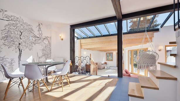 Un intérieur moderne comprenant un coin repas, un escalier et de grandes fenêtres.