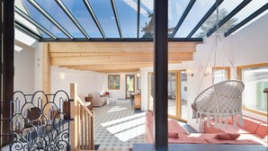 Un vaste espace de vie doté d’un haut plafond, d’un plancher en bois et d’une grande fenêtre laissant entrer la lumière naturelle.