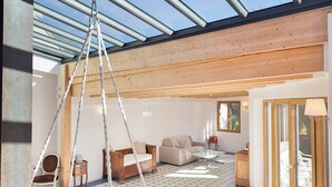 Un intérieur moderne avec un fauteuil suspendu, un canapé rouge et un plafond en bois.