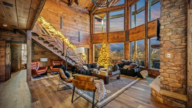 Ein geräumiges Wohnzimmer mit einer großen Treppe, Holzwänden und einem Weihnachtsbaum.
