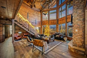 Un vaste salon agrémenté d’un grand escalier, de murs en bois et d’un sapin de Noël.