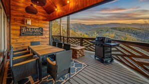 Eine Holzterrasse mit Grill, Korbmöbeln und einem Schild mit der Aufschrift 'Bar & Grill'.