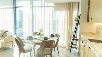 A modern living room with a dining area, large windows, and a kitchen with marble countertops.