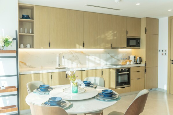 Una cocina moderna con armarios de madera, encimera de mármol y comedor con platos azules y un jarrón de flores.