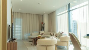 A modern living room with a sofa, ottomans, a coffee table, and a TV stand. - Pearlhouse Bahrain (Manama)