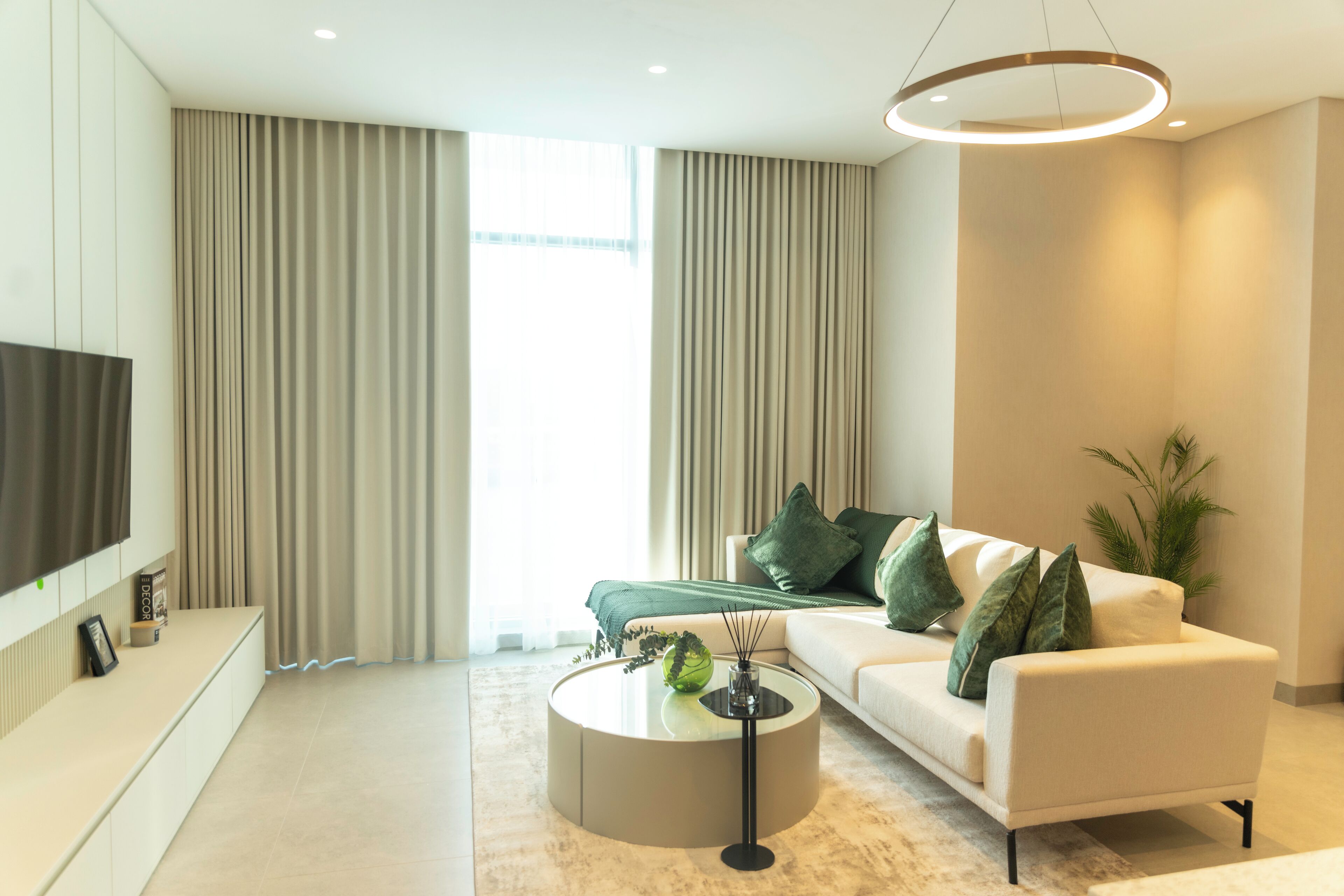 A modern living room with a sofa, a coffee table, and a TV mounted on the wall.
