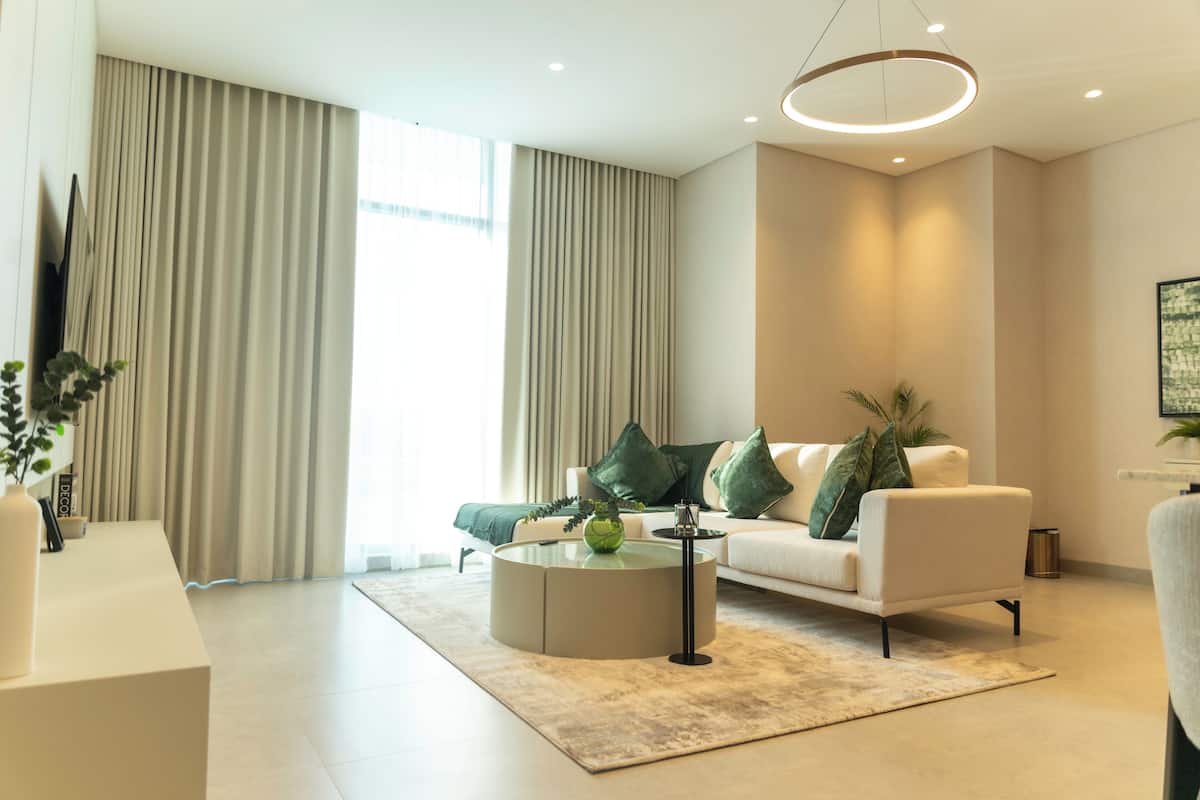A modern living room with a sofa, coffee table, and a large window with curtains.