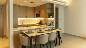 A modern kitchen with a marble countertop, built-in appliances, and a dining area with four chairs. - Pearlhouse Bahrain (Manama)
