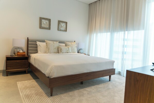 Un dormitorio moderno con una cama grande, una mesita de noche, una lámpara y dos obras de arte en la pared.
