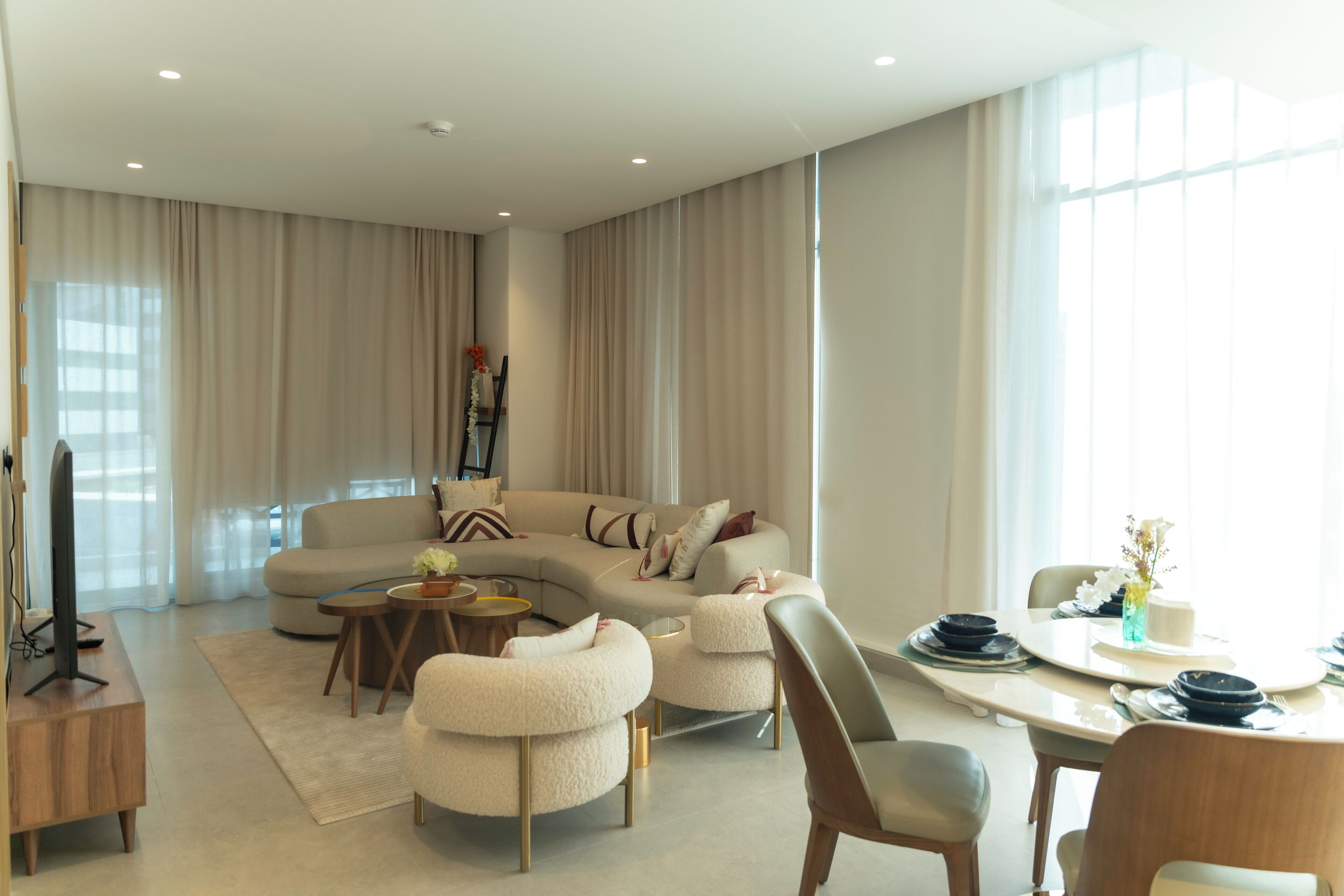 Un salon moderne avec un canapé aux lignes courbes, une table à manger et un téléviseur à écran plat.