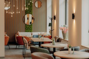 A modern interior with round tables, comfortable seating, and decorative lighting.