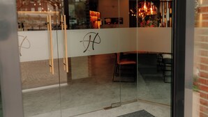 A modern interior with a glass partition featuring a logo, a brick wall, and a seating area with chairs and a table. - Stadthöfe Rhede by Hackmann (Rhede)