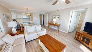 Un salón espacioso con un sofá blanco, una mesa de centro de madera y un mueble para televisor.