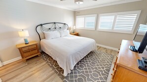 Un dormitorio con una cama, una mesita de noche con lámpara, un aparador y un televisor.