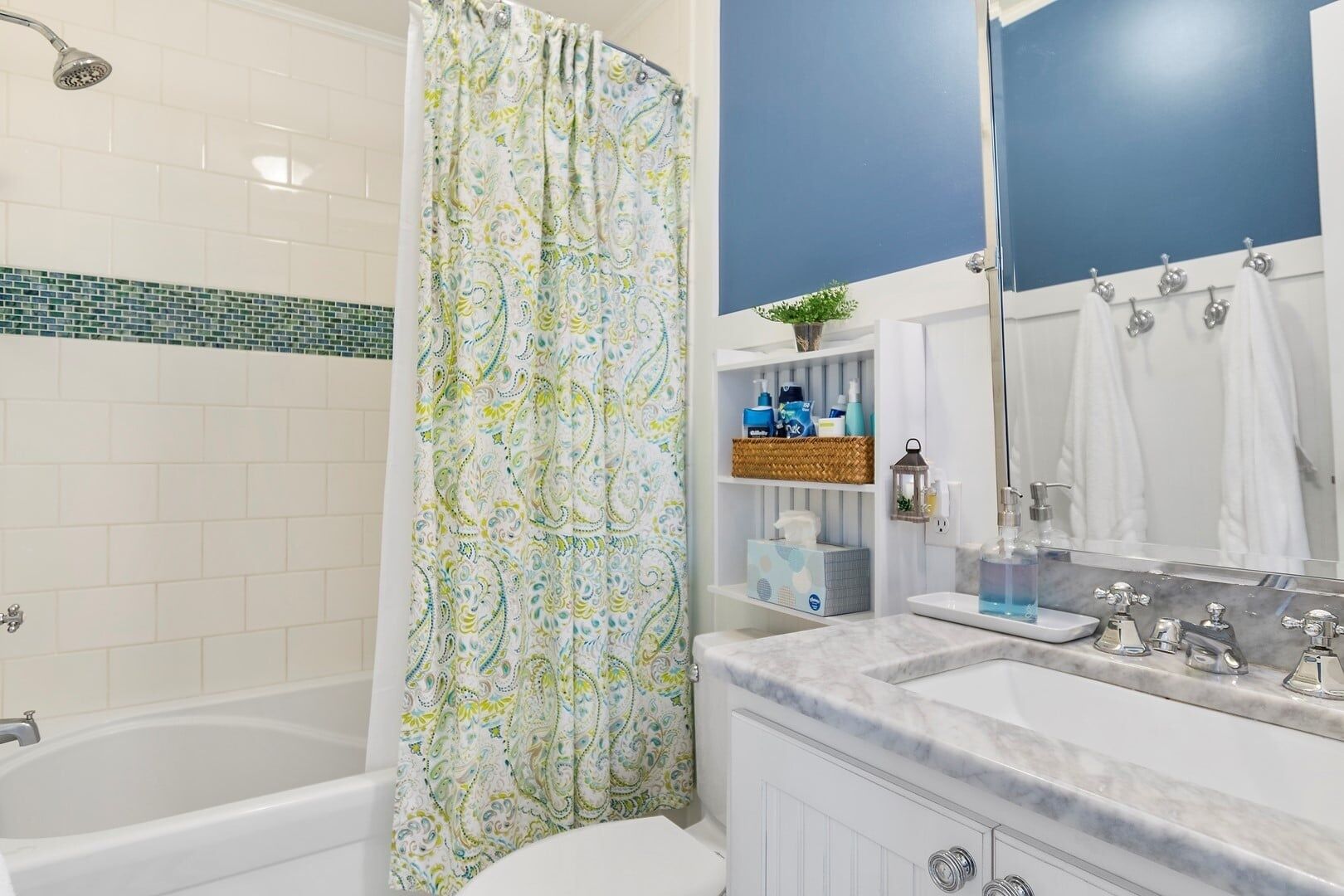 A bathroom with a bathtub, shower, and a vanity with a mirror and sink.