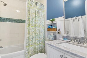 A bathroom with a bathtub, shower, and a vanity with a mirror and sink. - The Marlin House / 143 Marlin Drive 3 Bedroom Home (Supply)
