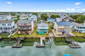 A coastal residential area with houses, a dock, and a calm water body. - The Marlin House / 143 Marlin Drive 3 Bedroom Home (Supply)