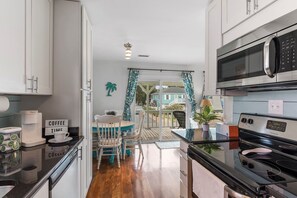 A modern kitchen with a coffee maker, microwave, and stove. - The Marlin House / 143 Marlin Drive 3 Bedroom Home (Supply)