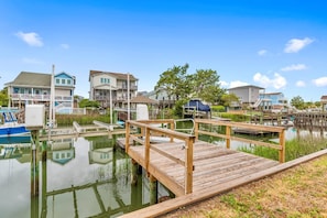 A waterfront property with a wooden dock, boats, and houses with balconies. - The Marlin House / 143 Marlin Drive 3 Bedroom Home (Supply)