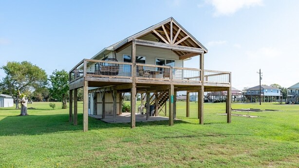 Une maison en bois à deux étages, dotée d’un balcon et entourée d’une pelouse.