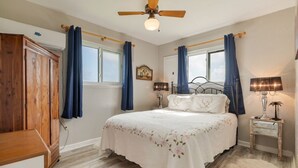 Une chambre à coucher comprenant un lit, un ventilateur de plafond, une table de chevet avec une lampe et une armoire.