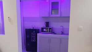 A compact kitchen with white cabinets, a microwave, a refrigerator, and a sink. - Comfort with elevator: complimentary breakfast buffet  (Dakar)