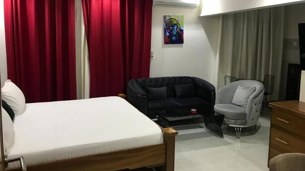 A bedroom with a bed, a black sofa, a grey armchair, and a small table with a red cup. - Comfort with elevator: complimentary breakfast buffet  (Dakar)