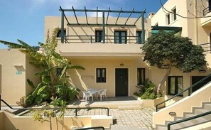A two-story building with a flat roof, a balcony, and a staircase leading to the entrance. - Rainbow Hotel Apartments (Chania)