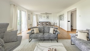 Un salón amplio con un sofá estampado gris, un sillón de lunares y una mesa de centro de mármol.