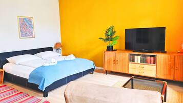 Una habitación de hotel con una cama, un televisor, un armario y una planta.