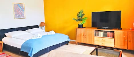 Una habitación de hotel con una cama, un televisor, un armario y una planta.