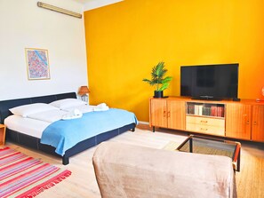 Une chambre d’hôtel avec un lit, une télévision, une armoire et une plante.