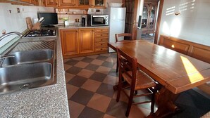 Eine Küche mit Holzschränken, einer Granit Arbeitsplatte, einem Herd, einer Spüle, einem Kühlschrank und einem Esstisch mit Stühlen.