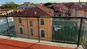 Ein Balkon mit Blick auf ein Wohngebiet, mit Terrakotta-Dachziegeln und einer Mischung unterschiedlicher Baustile.