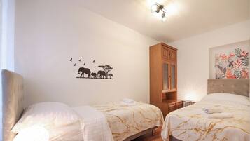 Habitación de hotel con dos camas, suelo de madera, un armario y un adhesivo mural con animales.