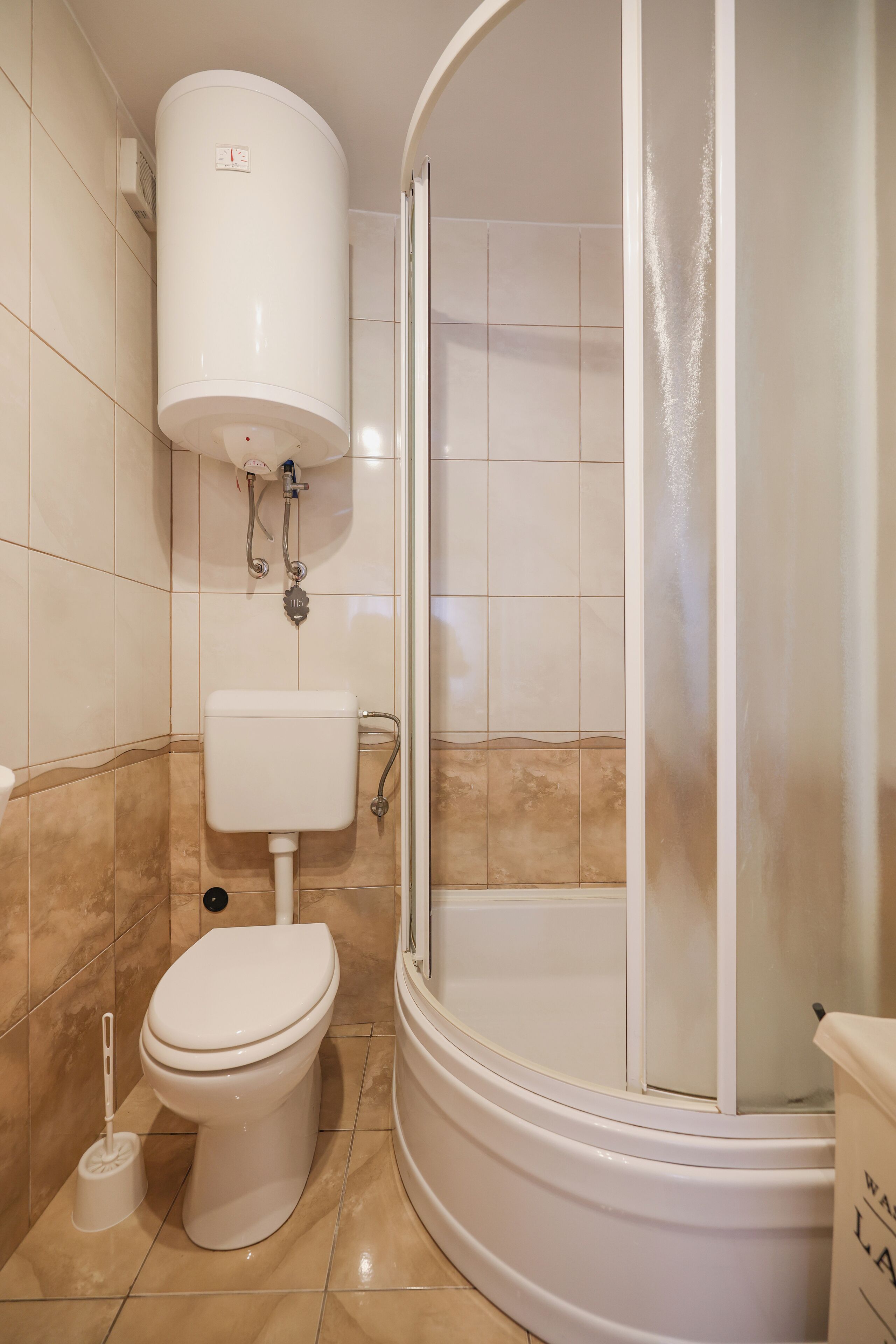 Ein Badezimmer mit Toilette, Duschkabine und einem an der Wand befestigten Toilettenpapierhalter.