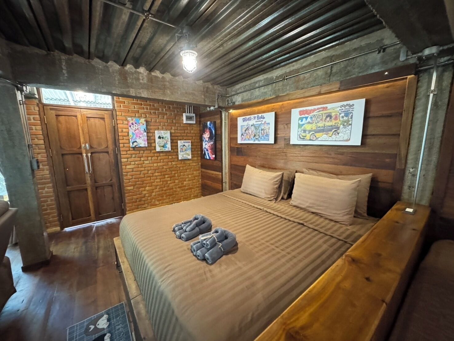 Une chambre avec un lit en bois, un mur en briques et des affiches accrochées au mur.