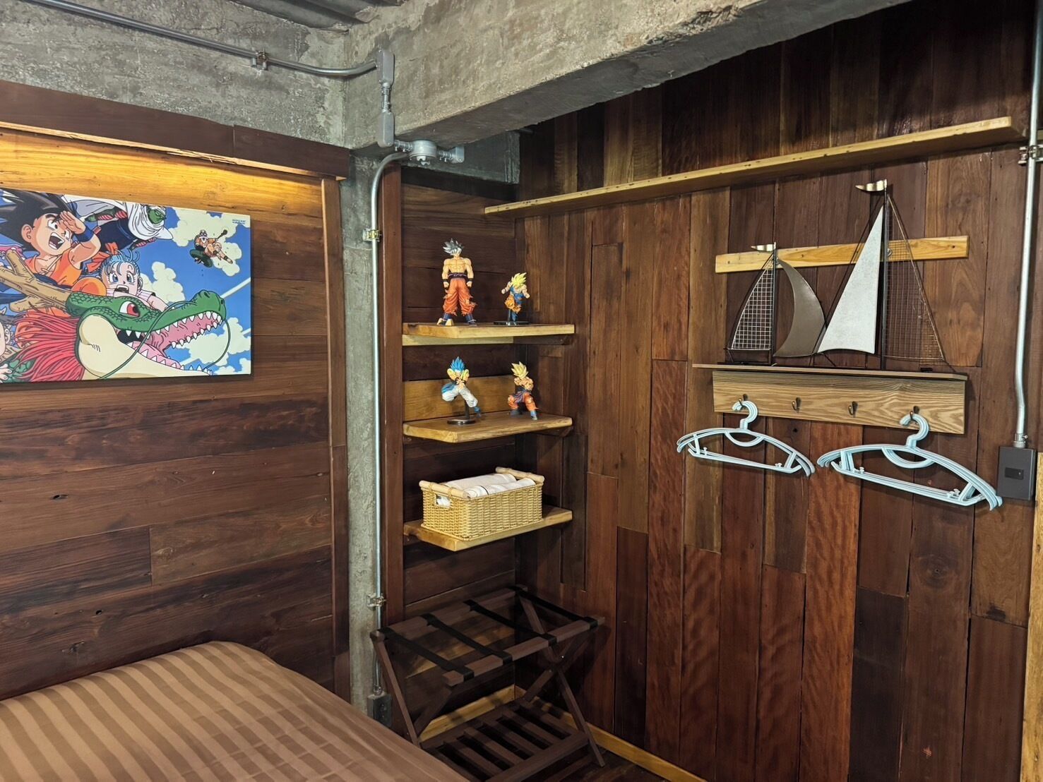 A room with wooden walls, a bed, a shelf with figurines, and a sailboat model.