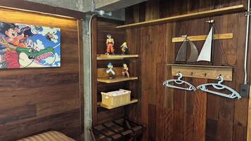 A room with wooden walls, a bed, a shelf with figurines, and a sailboat model.