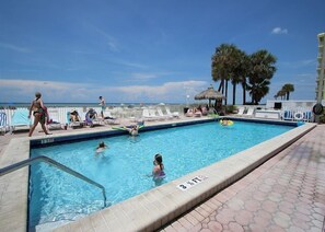 Relax by the pool surrounded by palm trees and lounge chairs.