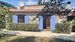A stone building with a tiled roof, a satellite dish, and a small entrance with a wooden door.