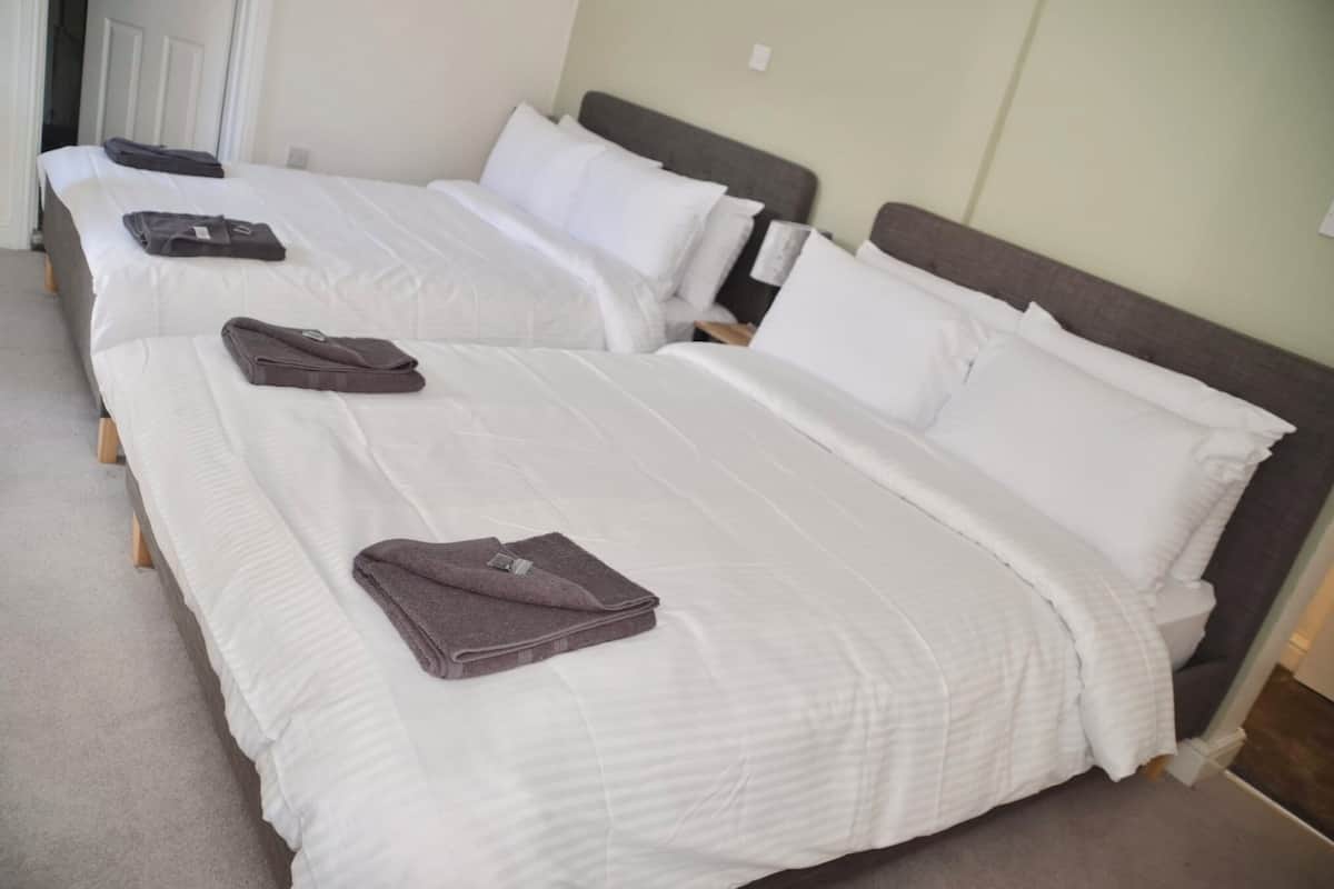 A hotel room with two beds, each with white bedding and pillows, and a brown headboard.