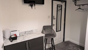 A bathroom with a white marble countertop, a black sink, a grey chair, a black TV mounted on the wall, and a door with a mirror. - Blok 3 by SB Stayz (Blackpool)