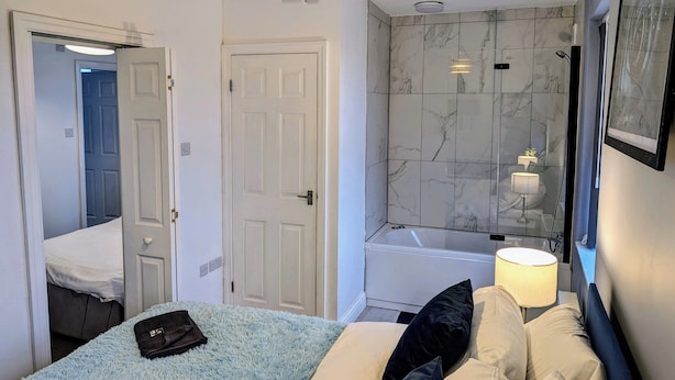 A hotel room with a bed, a bathroom with a bathtub, and a shower. - Blok 3 by SB Stayz (Blackpool)