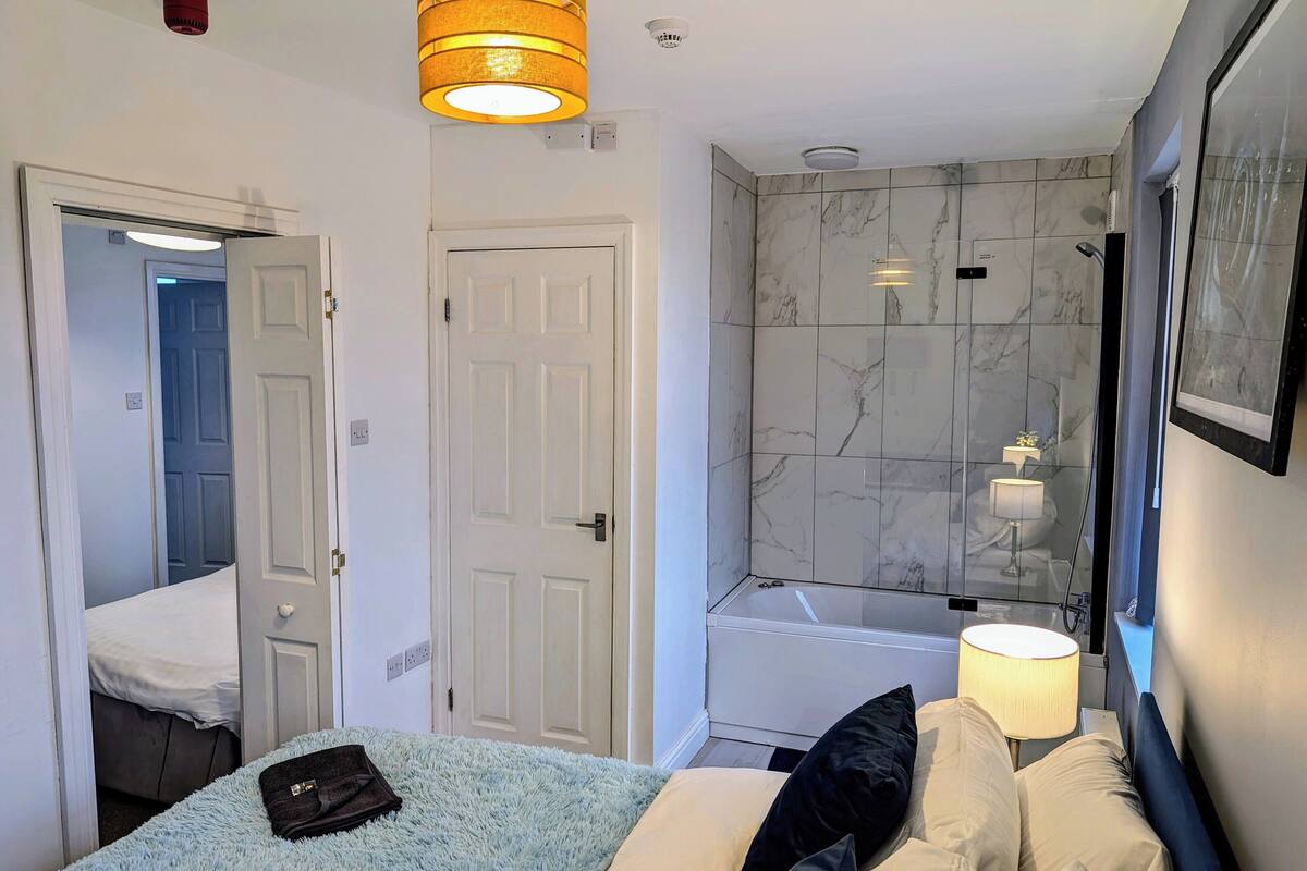 A hotel room with a bed, a bathroom with a bathtub, and a shower.