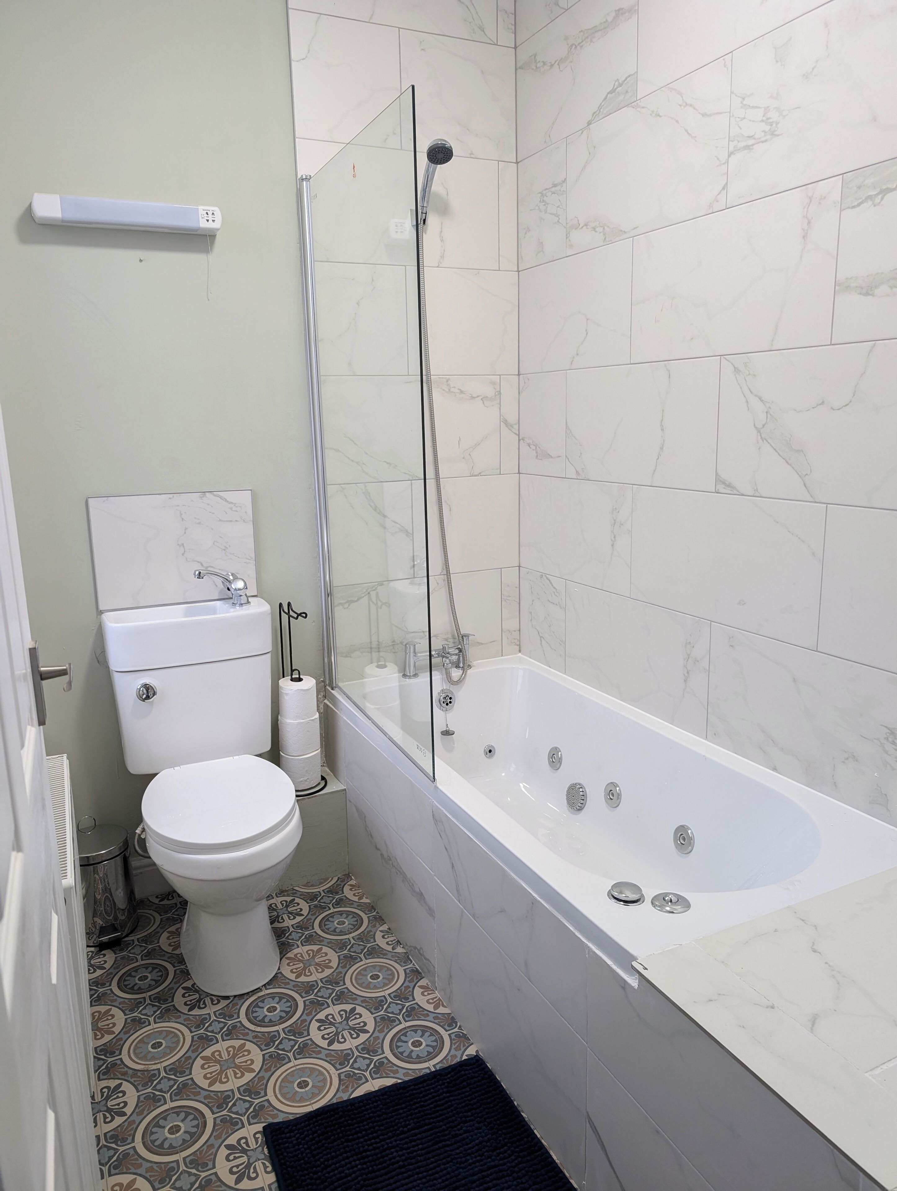 A bathroom with a toilet, a glass-enclosed shower, and a bathtub.