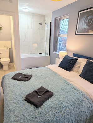 A bedroom with a bed, a window, a bathroom with a bathtub, and a toilet. - Blok 3 by SB Stayz (Blackpool)