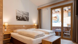 Ein Schlafzimmer mit einem hölzernen Bett, zwei Nachttischen mit Lampen, einer Bank und einem großen Fenster mit Blick auf ein Holzhaus.
