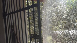 A covered outdoor area with a metal railing, steps leading to a seating area, and a chain-link fence enclosing the space. - Cat boarding 🐱 Travel  (Maracanã Jarinu)