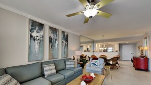 A modern living room with a grey sofa, a wooden coffee table, and a ceiling fan.